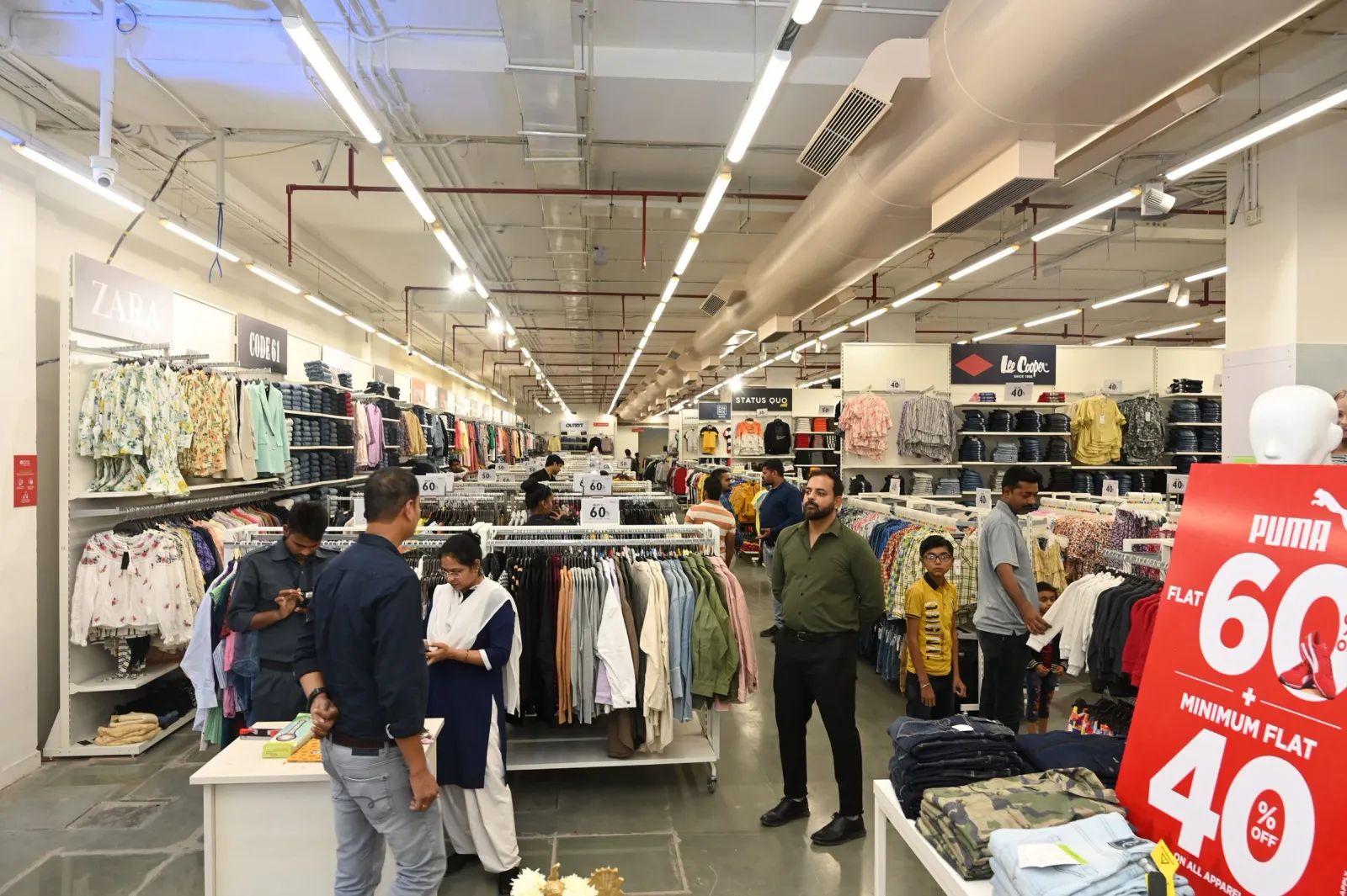 Shoppers and staff browsing clothing racks inside a newly launched fashion outlet