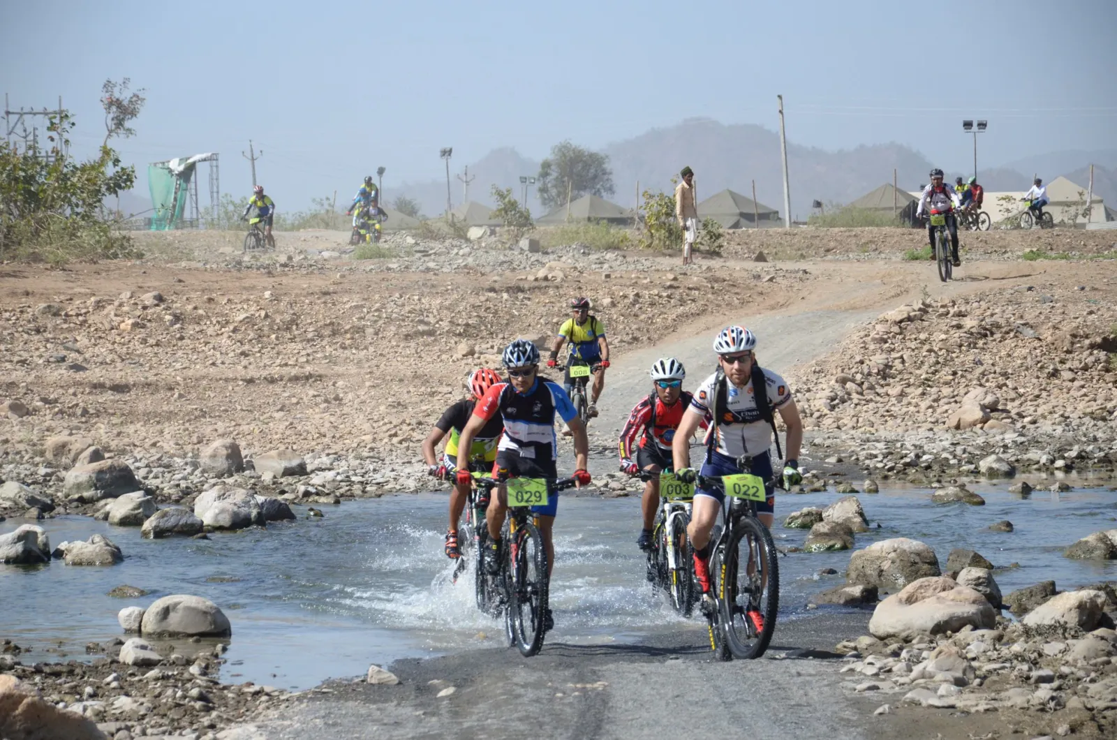 Mountain bike racers splashing through a rocky stream crossing during a cycling event