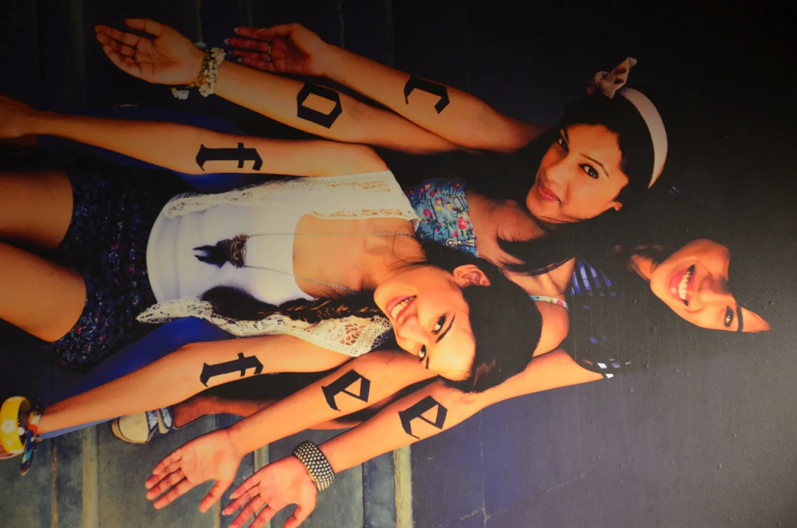 Wall graphic in a cafe showing three women with the letters of the word coffee painted on their arms, photographed sideways